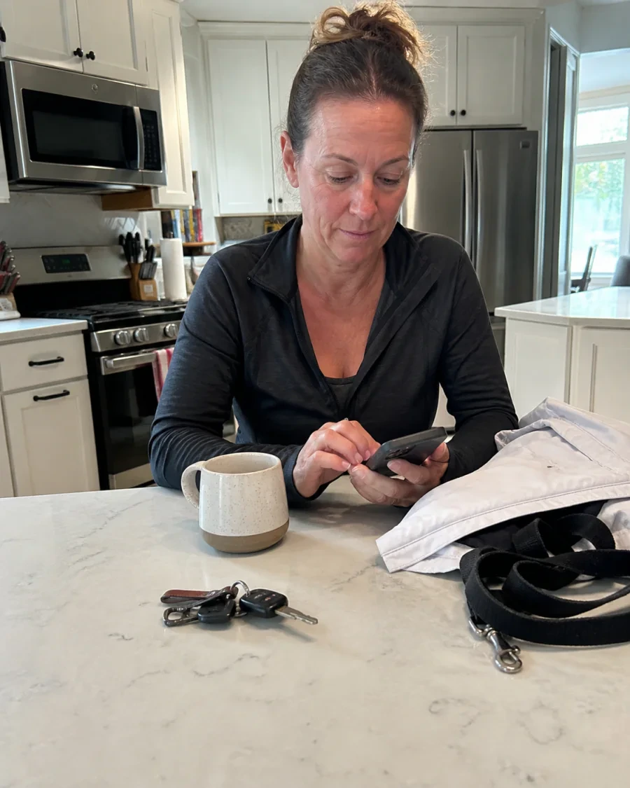 Woman finishing a neighborhood walk and checking her phone at a kitchen island